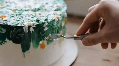 Hand finishing decorative details on a custom celebration cake